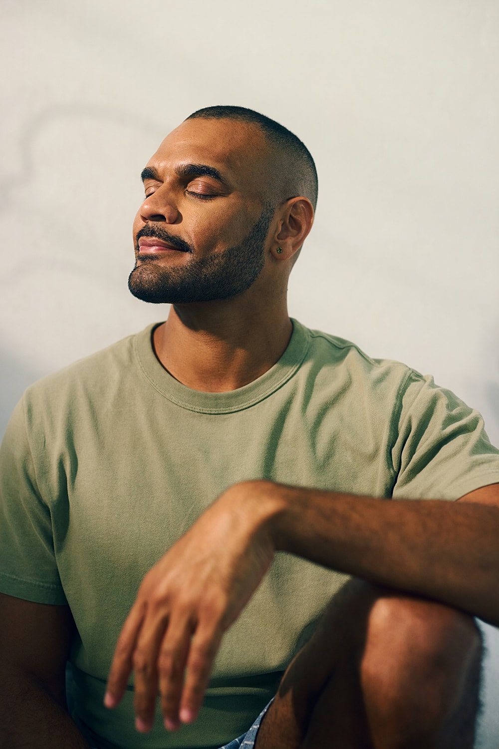 Man with closed eyes, relaxed expression, sitting.