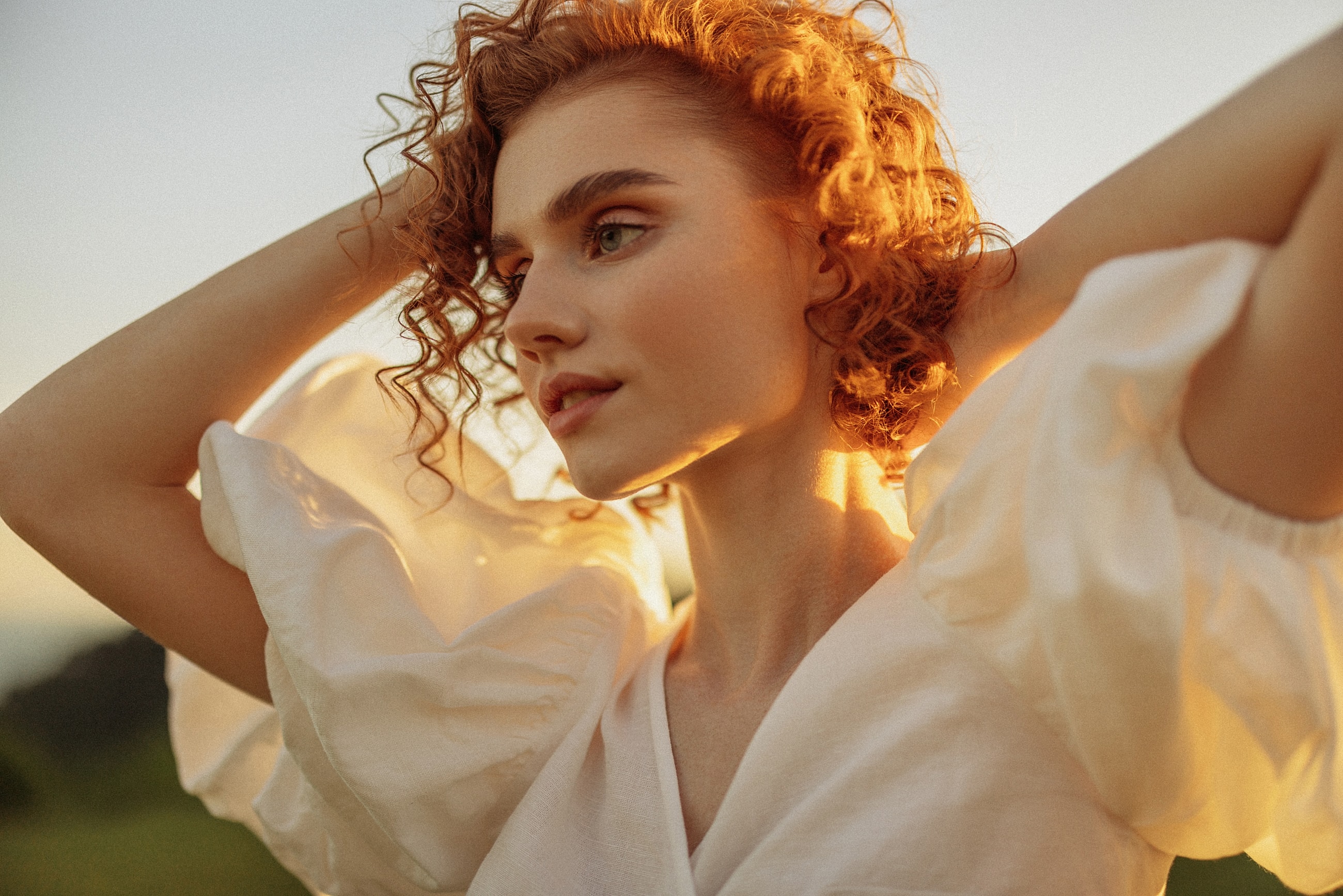 Woman with curly hair in golden sunset light.