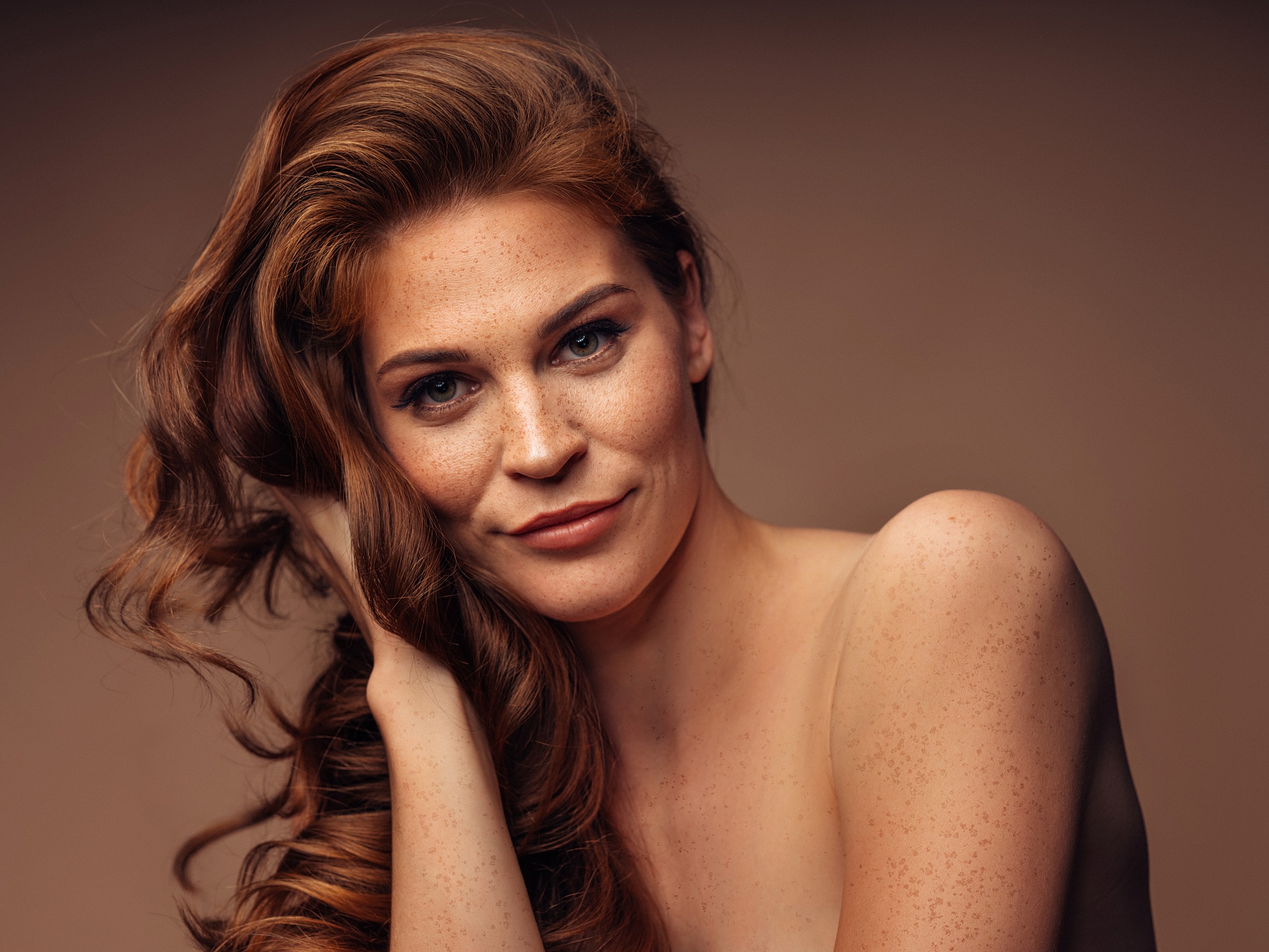 Woman with curly hair and freckles, soft expression.